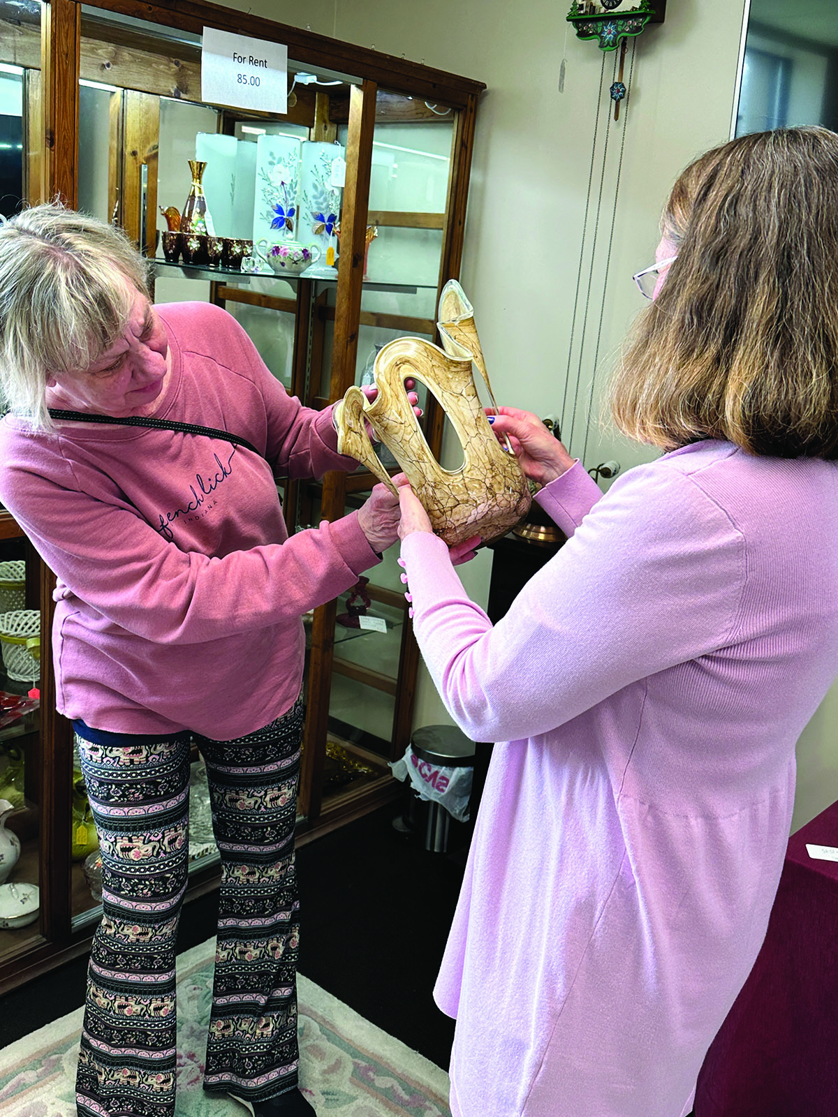 Two ladies looking at an antique vase.